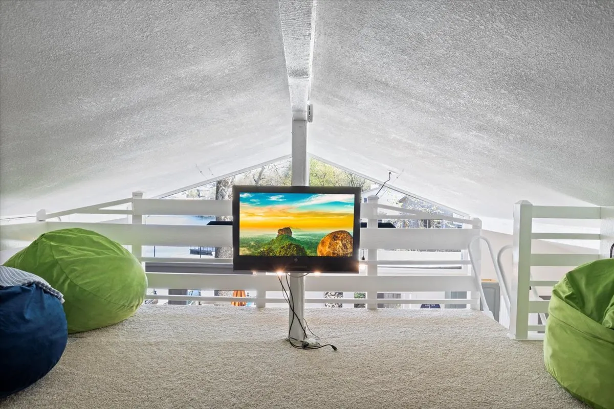 A spacious loft area with bean bag chairs, a mounted television, and a lofted ceiling. The room is casual and comfortable, suited for extra sleeping or as a play zone for kids and teens.