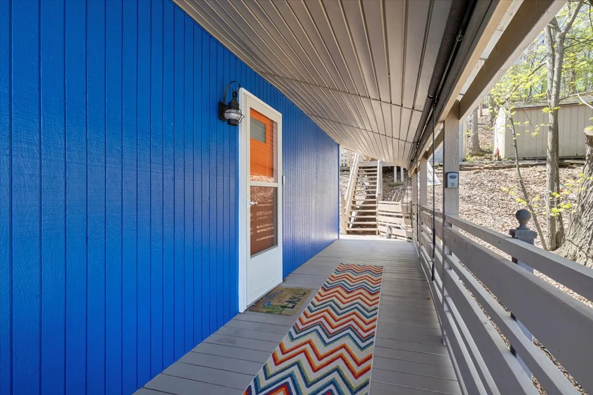 The bright blue exterior wall and white front door offer a welcoming first impression. The colorful zigzag rug and accessible entry point suggest an easy, secure arrival experience for guests.